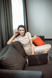 © VERSUSstudio - Young woman with modern laptop sitting on sofa at home