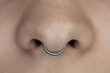 Nose piercing septum. Beautiful piercing jewelry. Macro shot. Selective focus.