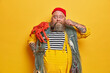 © wayhome.studio  - Indoor shot of bearded surprised man mariner curls mustache, smokes tobacco pipe and poses with fishing nets over yellow background. Plump fisherman enjoys successful day at sea shore, carries octopus