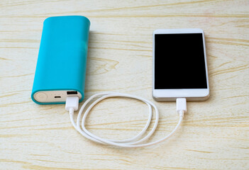 the smartphone is charged with a white wire from a power bank