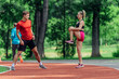 © qunica.com - Young couple stretching before starting their morning jogging routine on a tartan track at the park.