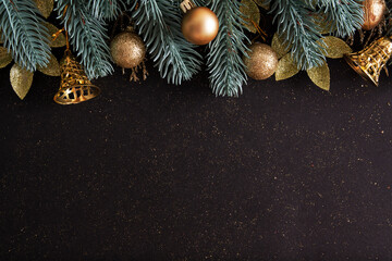 christmas layout with christmas trees, gold baubles and bells on a black background with copy space.
