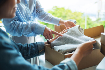 Wall Mural - Two young women receiving and opening a postal parcel box of clothing at home for delivery and online shopping concept