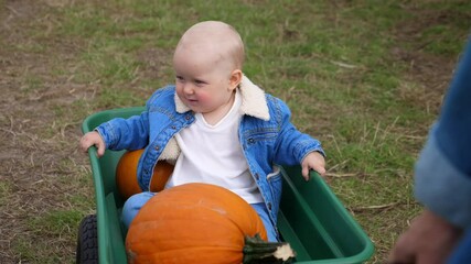 cute caucasian baby enjoying his ride with in a wagon at the pumpkin patch
