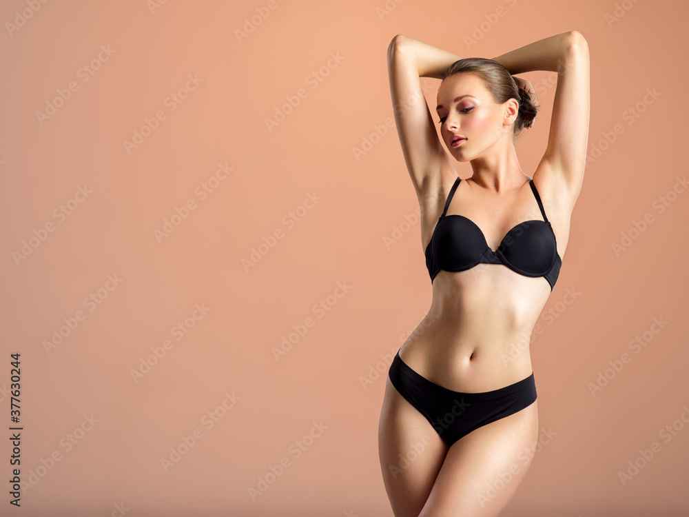 Young girl in black underwear with an ideal body, posing in the studio. - obrazy, fototapety, plakaty 