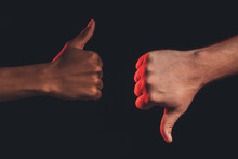 Like Dislike Gesture. Racial Disagreement. Closeup African Male Hand Thumb Up Caucasian Thumb Down Isolated On Dark. Ethnic Diverse. Black Lives Matter. No Racism