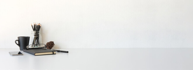 Wall Mural - Copy space minimal desk with books, coffee cup, smartphone and supplies with white wall background.