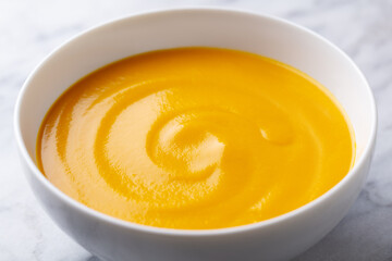 Wall Mural - Healthy comfort pumpkin, butternut squash soup in white bowl. Marble background. Close up.
