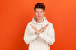 © khosrork - There is no way! Serious concentrated young man in stylish hoodie showing no gesture crossing arms, say no to bad habits, addiction. Indoor studio shot isolated on orange background