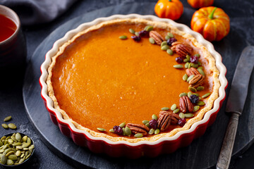 Wall Mural - Pumpkin pie, tart in baking dish. Black background. Close up. Copy space.