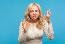 Aggressive Stressed Blond Woman Arguing And Becoming Mad Clenching Teeth, Crazy Furious Lady In Depression. Indoor Studio Shot Isolated On Blue Background