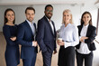 © fizkes - Portrait of smiling successful multiracial international businesspeople stand posing in office together. Happy motivated diverse multiethnic team show unity at workplace. Employment concept.