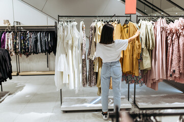 woman choosing elegant dress in clothing store