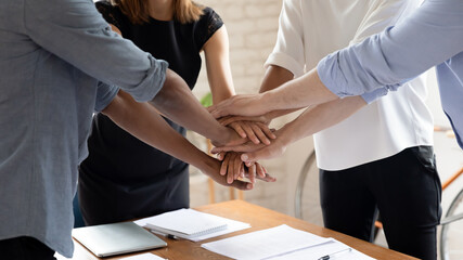 Sticker - Close up of diverse multiethnic colleagues stack hands in pile show support and help, motivated multicultural coworkers engaged in teambuilding activity at office meeting, teamwork concept