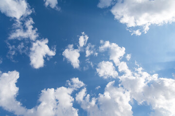 Wide angle perspective shot of clean blue limitless sky with clouds. Rays of the sun highlight the clouds.