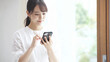 © aijiro - スマートフォンを操作している若い女性