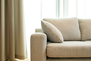 close up light beige fabric sofa with warm cozy morning light from big window home interior background