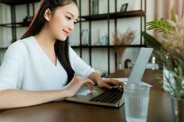 Asian young mother working at home using computer for working from distance whilestay quarantine together with family new normal lifestyle work from home Due to Covid19 virus spread epidemic