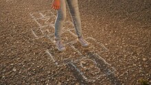 Girl Child Playing Classics Hopscotch Game In The Park. Childhood Kid Dream Concept. Little Girl Jumping On The Squares Game Hopscotch. Fun Kid Playing Outdoors Dream Of Happiness