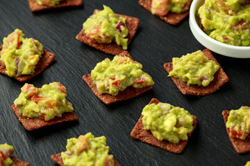 Wall Mural - Avocado Guacamole with chipotle and poblano whole grain tortilla chips on rustic stone board