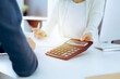 © Iryna - Accountant checking financial statement or counting by calculator income for tax form, hands close-up. Business woman sitting and working with colleague at the desk in office. Audit concept