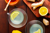 Fototapeta  - Ginger tea with lemon. Two cups of ginger tea with lemon and honey on wooden background. Top view