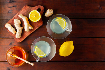 Wall Mural - Ginger tea with lemon. Two cups of ginger tea with lemon and honey on wooden background. Top view