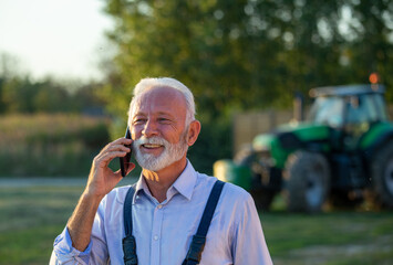 Sticker - Senior farmer talking on mobile phone in front of tractor