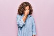 Middle age beautiful woman wearing casual denim shirt standing over pink background tired rubbing nose and eyes feeling fatigue and headache. Stress and frustration concept.