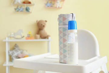 Canvas Print - Bottle of milk for baby on high chair in room