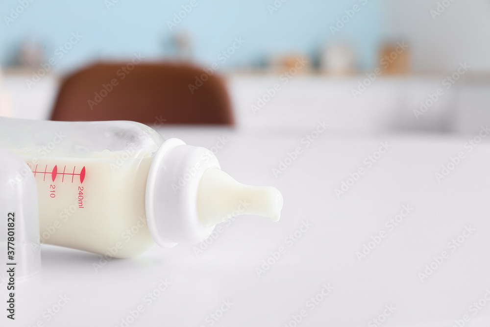Bottle of milk for baby on table in kitchen