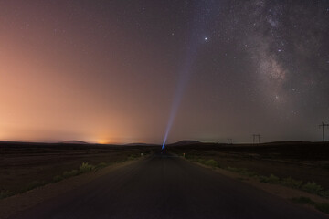 Wall Mural - Milky Way on night sky and standing man silhouette on road with flashlight . Colorful night landscape. Exploring the universe