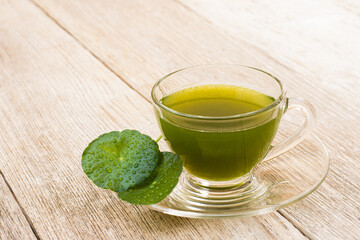 Wall Mural - Glass cup of Gotu Kola juice tea with green leaves ( Asiatic pennywort, Indian pennywort, Centella asiatica ) isolated on wood board background.