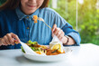 Closeup image of a beautiful asian woman eating fish and chips on table in the restaurant