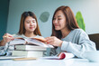 © Farknot Architect - Two young female students tutoring and catching up workbook together