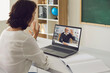 © Studio Romantic - Education training teaching online. Female teacher greets senior male university student using laptop video call online.