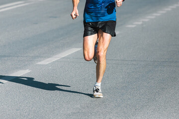 Wall Mural - Running sports. Man runner legs and shoes in action on the road outdoors at sunset. Male athlete model