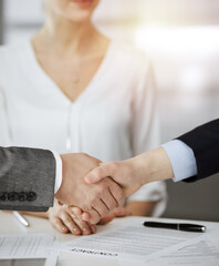 Business people shaking hands finishing contract signing in sunny office, close-up. Handshake and marketing