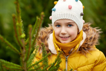 Sticker - winter holidays and people concept - close up of happy smiling little girl choosing christmas tree at street market