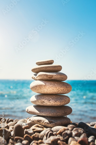 A pyramid of sea pebbles on the shore of the blue sea - balance and balance - harmony, serenity and peace