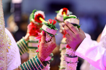 The hands of Indian bride and groom holding varmala.