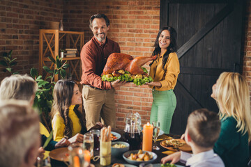 Poster - Young marriage parents hold decorated apples stuffed big turkey holiday dinner family reunion living room indoors