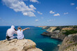 © ruslanshug - man and woman sitting together on mountain looking at beautiful nature on sea resort at summer or autumn