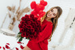 © Тарас Нагирняк - blonde young woman holding big bouquet of red roses with heart shaped balloons on the background in the bedroom.