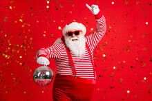 Photo Of Retired Old Man Grey Beard Hold Vintage Disco Ball Dance Funky Wear Santa X-mas Costume Suspenders Sunglass Gloves Striped Shirt Cap Isolated Red Color Background