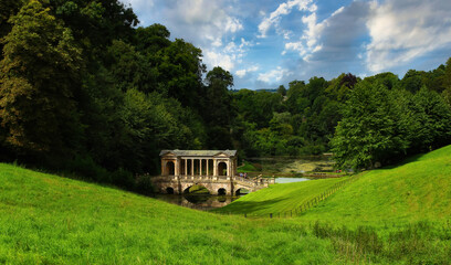 Mystical landscape, Prior Park, and Palladian Bridge. View for fresh grass, trees, river with blue sky.