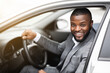 Cheerful successful black businessman looking through car window