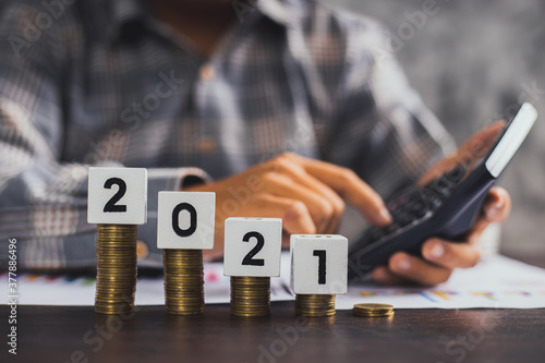 save and financial management concept, close up hand of business man calculate economy cash and  stacked money of coins and invest in currency in 2021 year