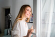 © leszekglasner - Beautiful smiling woman opening window at the morning