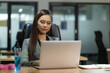 © Nopphon - Young asian businesswoman using laptop sitting in modern office working with social distancing alcohol gel on desk.